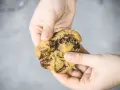 Hände halten einen zerkrümelten Schokoladenkeks, der nach einem einfachen Cookies Rezept gemacht wurde.