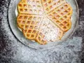 Herzförmige Bananenwaffeln, bestäubt mit Puderzucker, auf einem Teller. Ein süßer Genuss für jeden Tag.