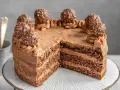 Schokoladige nougat torte mit Ferrero Rocher Kugeln und zarter Schokoladencreme. Ein Stück fehlt bereits.