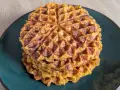 Ein Stapel goldbrauner Haferflocken Waffeln auf einem dunklen Teller. Sie sehen knusprig und lecker aus, perfekt für ein gesundes Frühstück.
