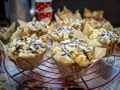 Saftige Nutella Muffins mit Streuseln und Schokoglasur, verpackt in Zeitungspapier-Förmchen, auf einem roten Gitter.