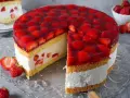 Eine saftige Erdbeer Sahne Torte mit frischen Erdbeeren und Tortenguss, ein Stück ist bereits angeschnitten.