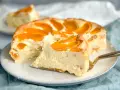 Ein saftiger Pfirsichkuchen mit cremiger Füllung und frischen Pfirsichspalten. Ein Stück wird gerade mit einem goldenen Tortenheber herausgehoben.