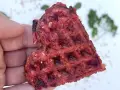 Herzhafte Waffeln aus Roter Bete, gehalten von einer Hand. Ein gesunder Snack mit leckerer Textur.