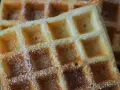 Goldbraune Waffeln, bestäubt mit Puderzucker, warten auf Joghurt. Ein süßer Genuss!