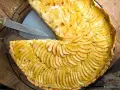 Ein köstliches Apfeltarte Rezept mit dünn geschnittenen Äpfeln, die wie Fächer angeordnet sind. Ein Stück wurde bereits herausgeschnitten.