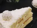 Ein Stück Raffaello Torte, bedeckt mit Kokosraspeln und einer Raffaello-Kugel.
