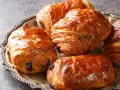Einige goldbraune, knusprige Pain au Chocolat liegen auf einer silbernen Platte.