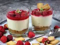 Zwei leckere Desserts im Glas mit Himbeeren und Keksen, ein süßer Genuss.