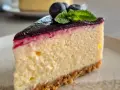 Ein Stück cremiger Blueberry Cheesecake mit Blaubeersauce, frischen Blaubeeren und Minze.