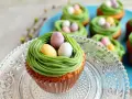 Oster-Cupcakes mit grünem Frosting als Nest und bunten Schokoladen-Eiern.