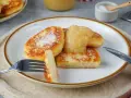 Goldbraune Quarkkeulchen, bestreut mit Puderzucker, serviert mit Apfelmus. Ein köstliches Quarkkeulchen Rezept zum Genießen.