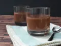 Zwei Gläser cremiger Schokopudding, perfekt zum Schokopudding selber machen. Ein Löffel liegt bereit.
