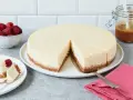 Ein cremiger New York Cheesecake mit knusprigem Boden, garniert mit Himbeeren und Karamell.
