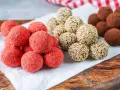 Drei Sorten leckere Energy Balls: rote Erdbeer-Bällchen, mit Sesam umhüllte Kugeln und schokoladige Trüffel.