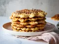 Ein Stapel goldbrauner Quarkwaffeln, bestäubt mit Puderzucker. Perfekt für ein schnelles Quarkwaffeln Rezept.