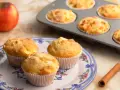 Frisch gebackene Apfelmus Muffins auf einem Teller, daneben Äpfel und Zimt.