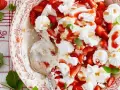 Ein köstlicher Eton Mess mit frischen Erdbeeren, Baiser und Sahne, garniert mit Mandelsplittern und Minze.