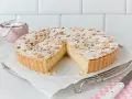 Eine köstliche Torta della Nonna, bestäubt mit Puderzucker und Pinienkernen, wartet darauf, angeschnitten zu werden.