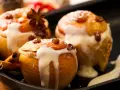 Drei köstliche Bratäpfel, übergossen mit Vanillesauce und garniert mit Rosinen und Zimtstangen. Ein perfektes Bratapfel Rezept für kalte Tage.