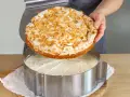 Eine köstliche Stachelbeer Baiser Torte mit Mandel-Topping wird gerade in einen Tortenring gesetzt.