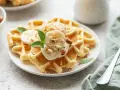 Goldbraune Skyr Waffeln mit Bananenscheiben, gehackten Mandeln und Minze. Ein köstlicher Start in den Tag!