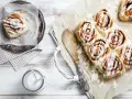 Frisch gebackene schwedische Zimtschnecken mit Zuckerguss, serviert mit einem Glas Milch.