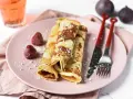 Gefüllte Pfannkuchen ohne Mehl, bestäubt mit Puderzucker, serviert mit Erdbeeren und Feigen.