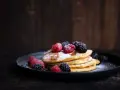 Stapel goldbrauner Pancakes, bestäubt mit Puderzucker und garniert mit frischen Himbeeren und Brombeeren. Ein köstliches Pancakes Rezept für jeden Anlass.
