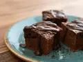 Saftige Brownies, perfekt für ein schnelles Brownie Rezept. Mit flüssiger Schokolade übergossen und auf einem türkisfarbenen Teller angerichtet.