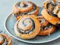 Saftige Mohnschnecken mit Zuckerguss auf einem blauen Teller. Dieses Bild inspiriert zum Nachbacken mit einem einfachen Mohnschnecken Rezept.