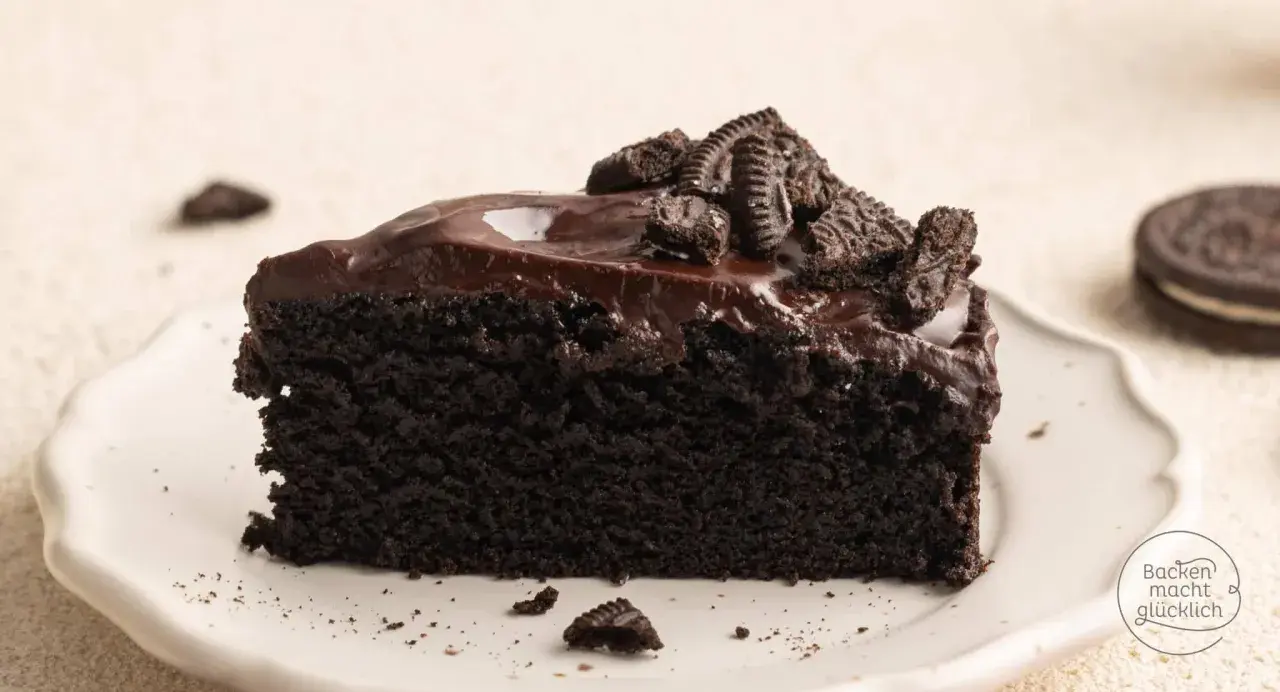 Ein saftiges Stück dunkler Oreo Kuchen mit glänzender Schokoladenglasur und zerbröselten Keksen obendrauf.
