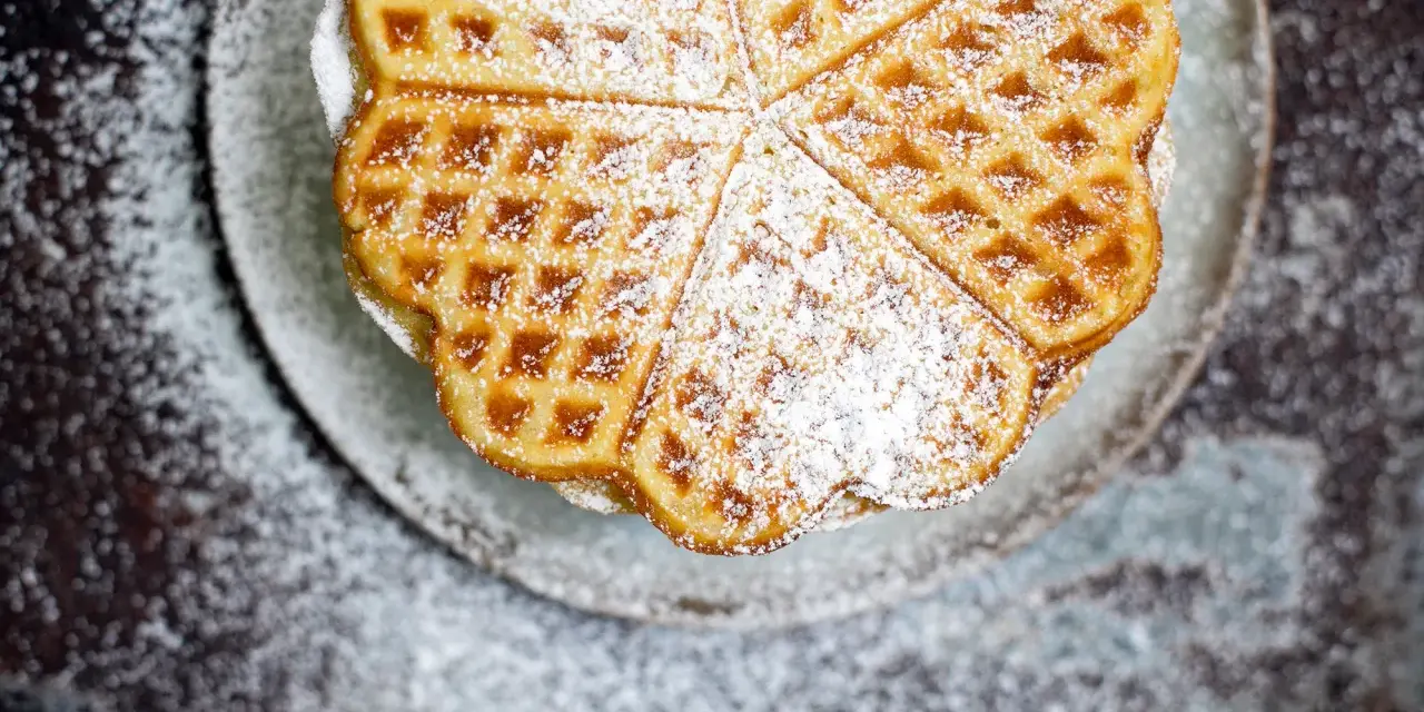 Herzförmige Bananenwaffeln, bestäubt mit Puderzucker, auf einem Teller. Ein süßer Genuss für jeden Tag.