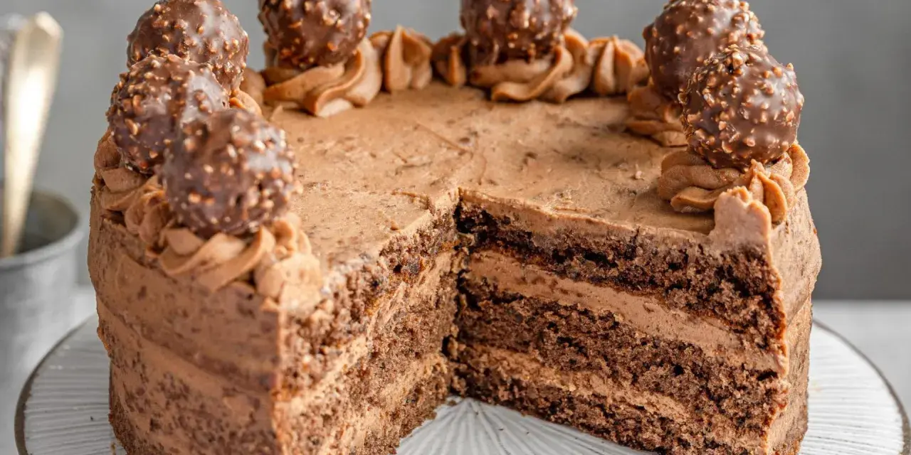 Schokoladige nougat torte mit Ferrero Rocher Kugeln und zarter Schokoladencreme. Ein Stück fehlt bereits.
