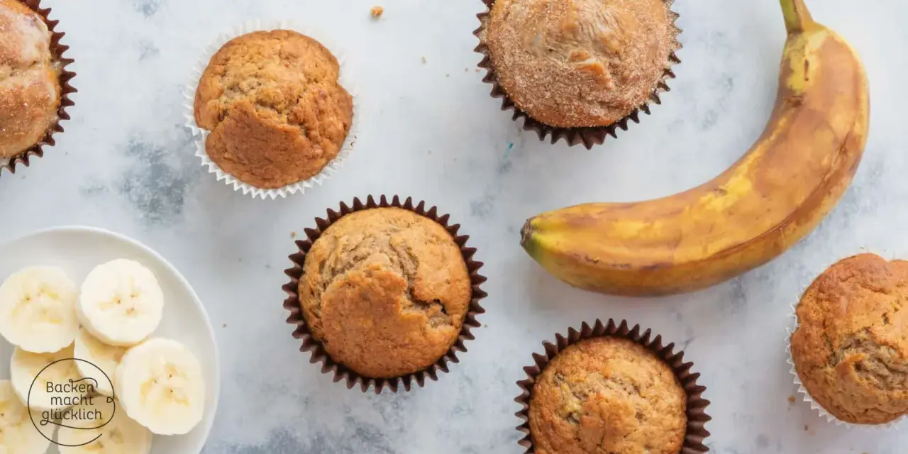Leckere Bananen Muffins, frisch gebacken, mit einer reifen Banane und Bananenscheiben daneben.