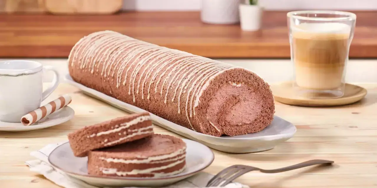 Eine köstliche schoko biskuitrolle mit weißer Glasur, dane zwei Scheiben und ein Kaffee.