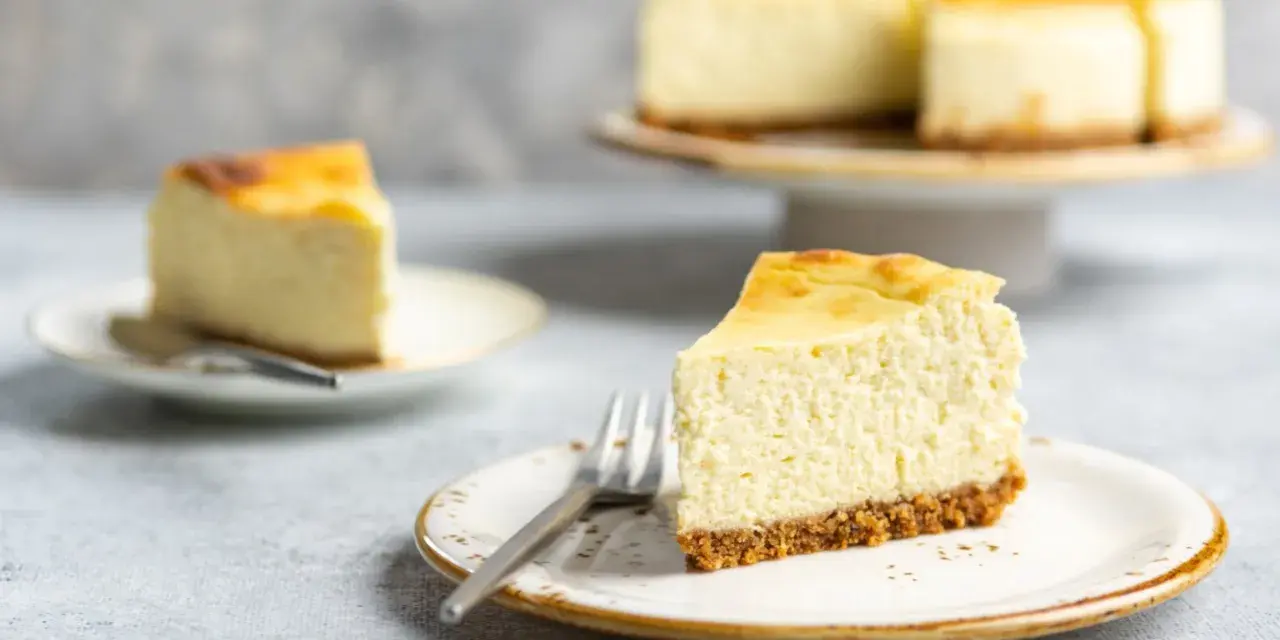 Ein cremiger Kuchen mit Mascarpone, auf einem Teller mit Gabel, daneben ein weiteres Stück und ein ganzer Kuchen.