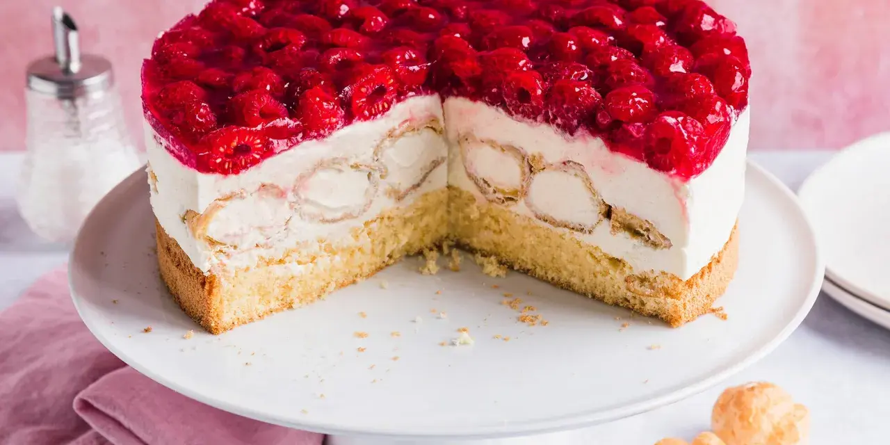 Eine köstliche Windbeutel Torte mit frischen Himbeeren und Sahne. Kleine Windbeutel sind in die cremige Füllung eingebettet.