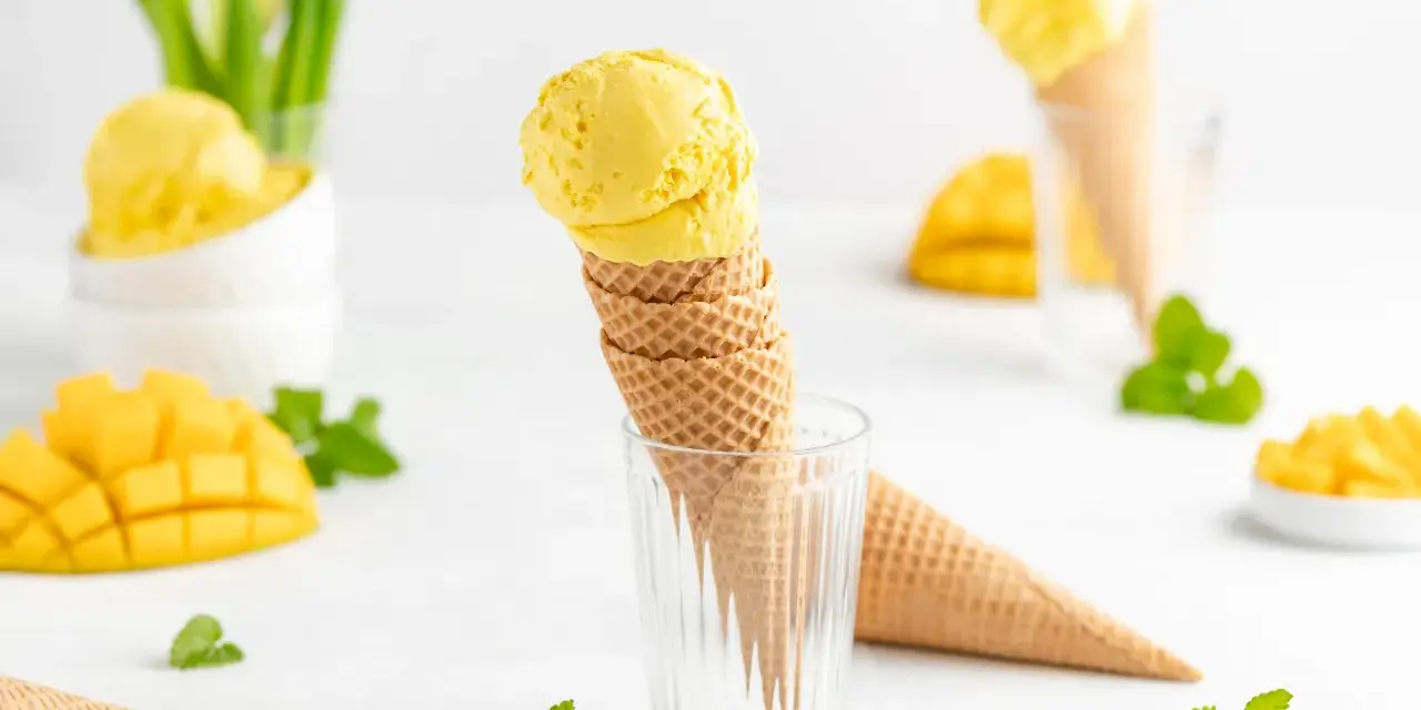 Ein Stapel Waffelkegel mit cremigem Mango Eis, garniert mit frischer Minze und Mangostücken. Ein süßer Genuss!