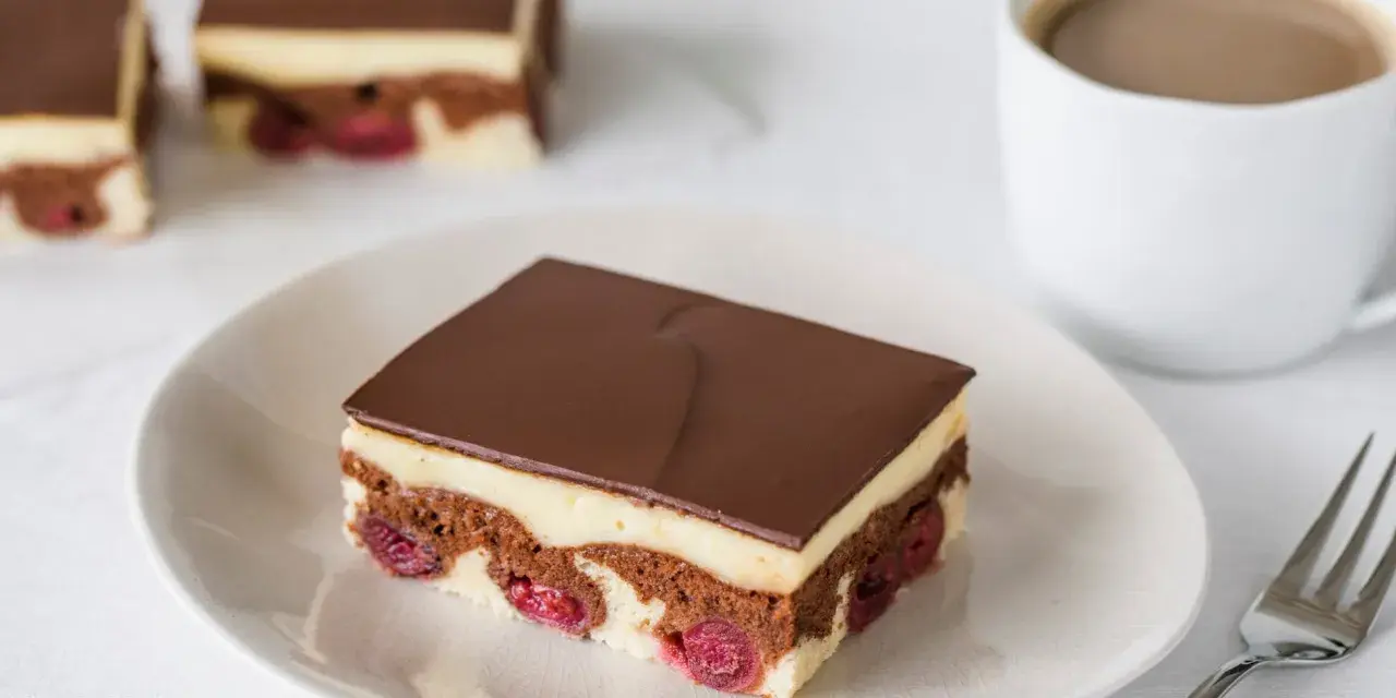 Ein Stück Donauwelle-Kuchen mit Kirschen, Vanillecreme und Schokoladenglasur. Ein leckeres Rezept für den Kaffeetisch.