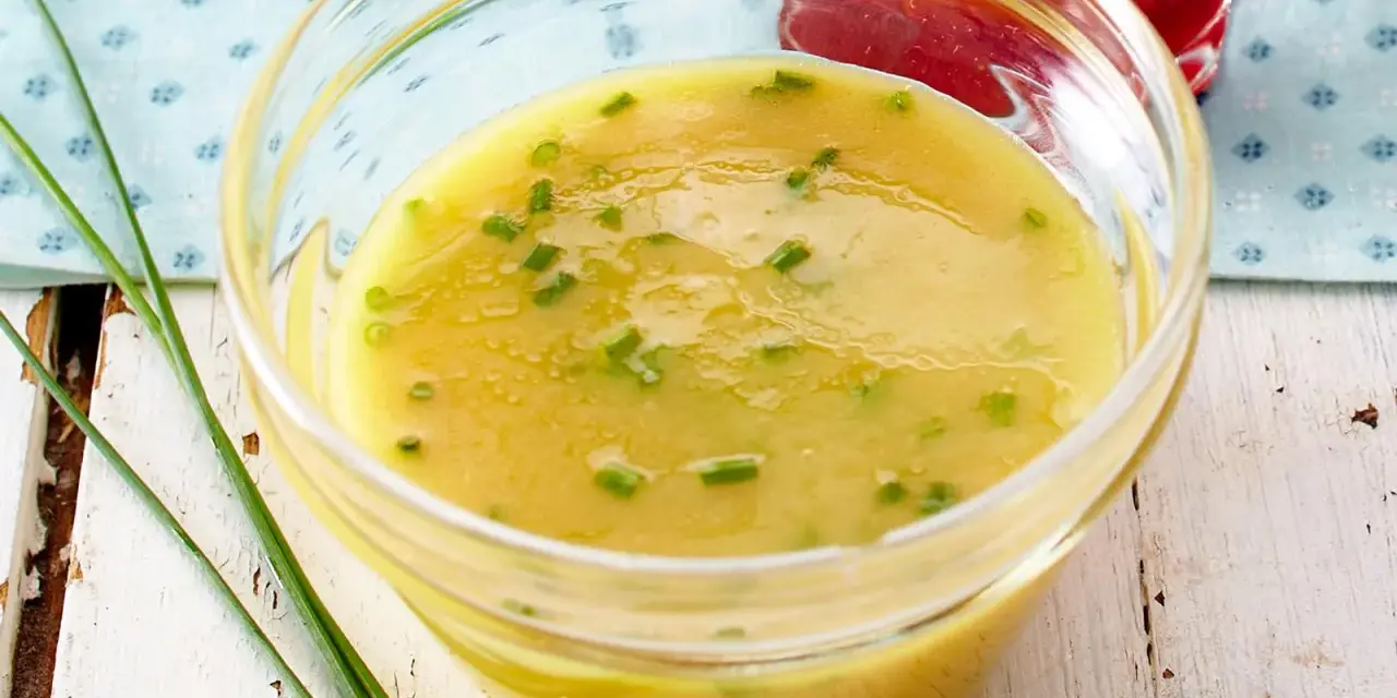 Ein Glas mit cremigem honig senf dressing, garniert mit Schnittlauch. Perfekt für Salate.