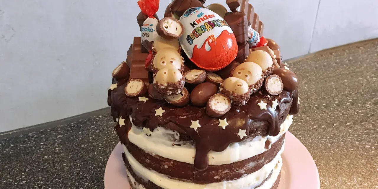 Schokoladentorte mit Kinder-Überraschungsei, Schoko-Bons und vielen weiteren Süßigkeiten dekoriert.