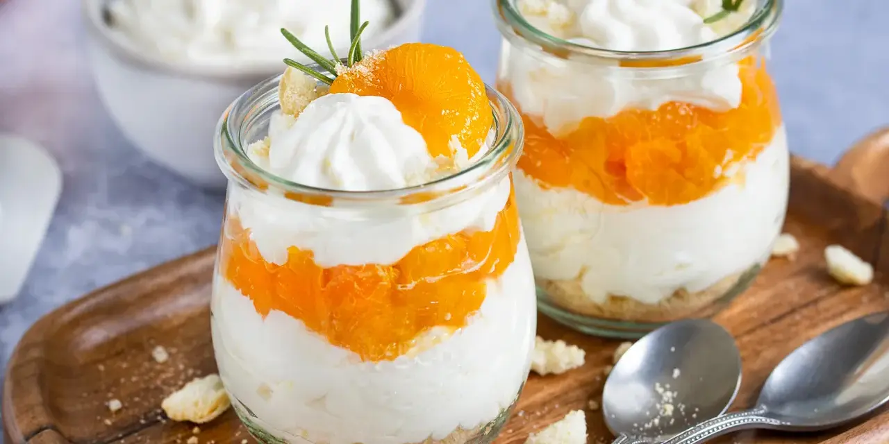 Zwei Gläser mit einem schnellen Dessert aus Mandarinen und Sahne, garniert mit Rosmarin.