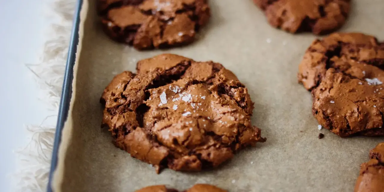 Saftige schoko cookies mit Meersalzflocken auf Backpapier, bereit zum Genießen.