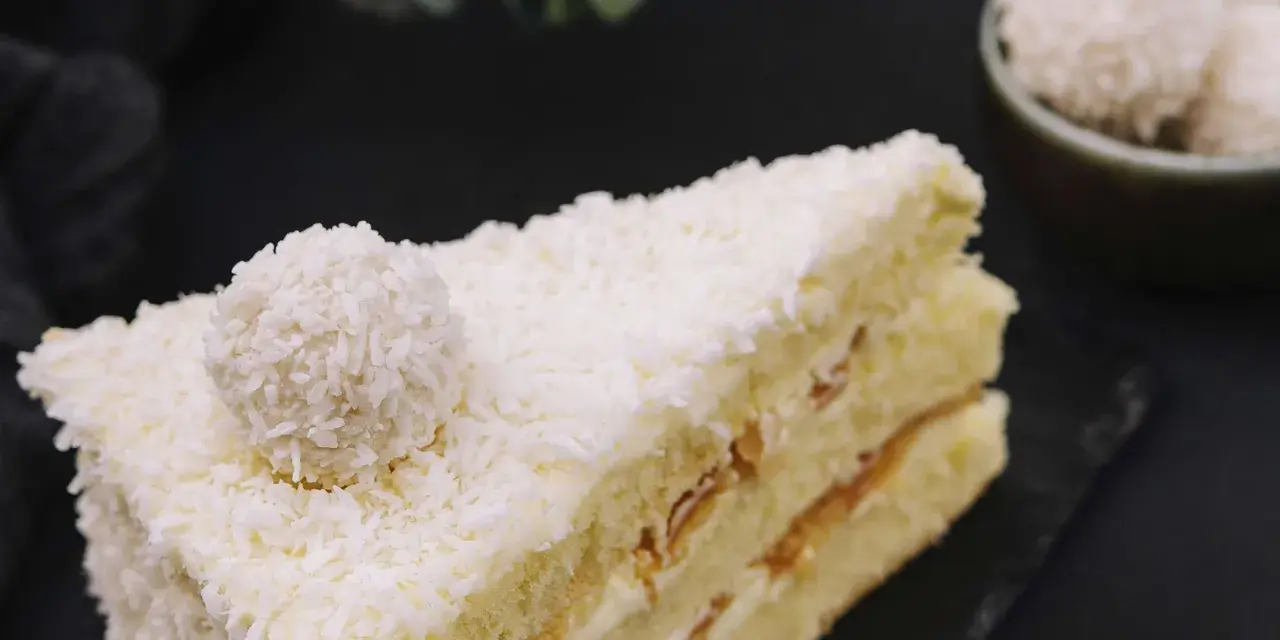 Ein Stück Raffaello Torte, bedeckt mit Kokosraspeln und einer Raffaello-Kugel.