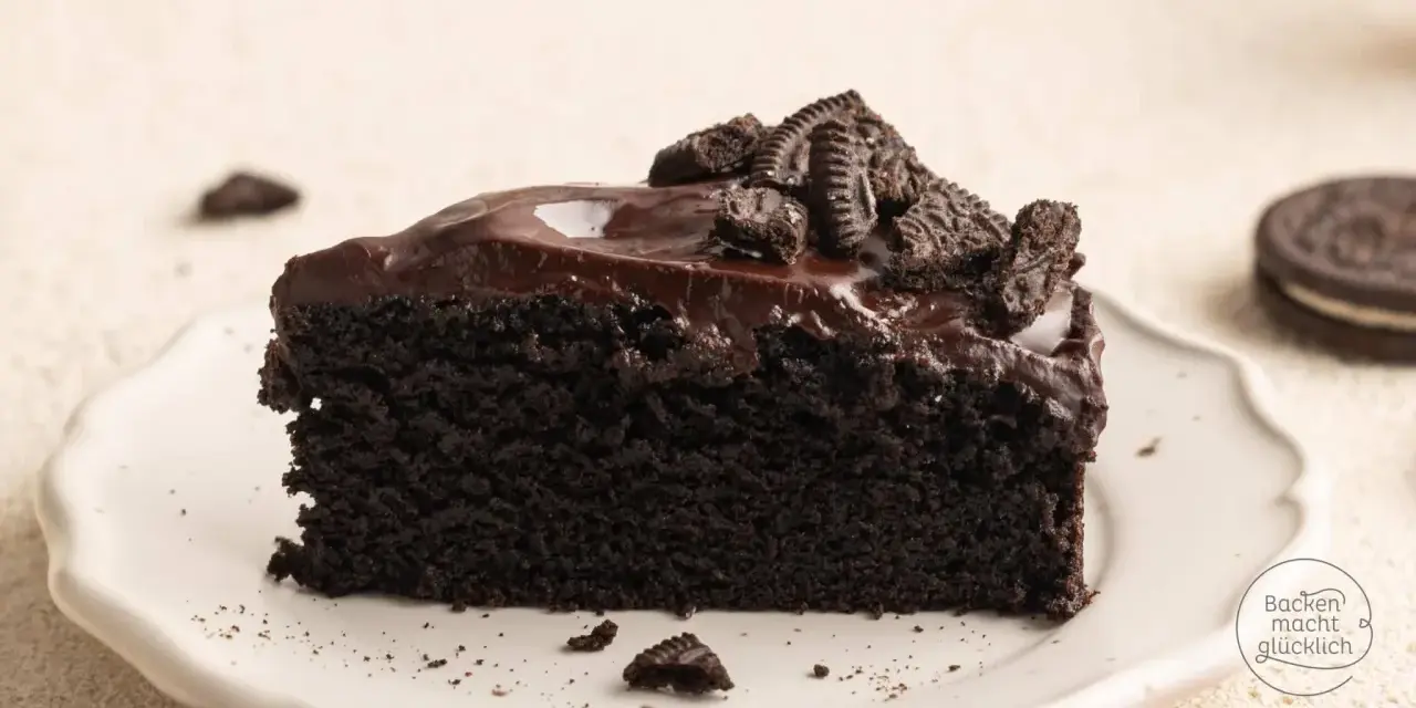Ein saftiges Stück dunkler Oreo Kuchen mit glänzender Schokoladenglasur und zerbröselten Keksen obendrauf.
