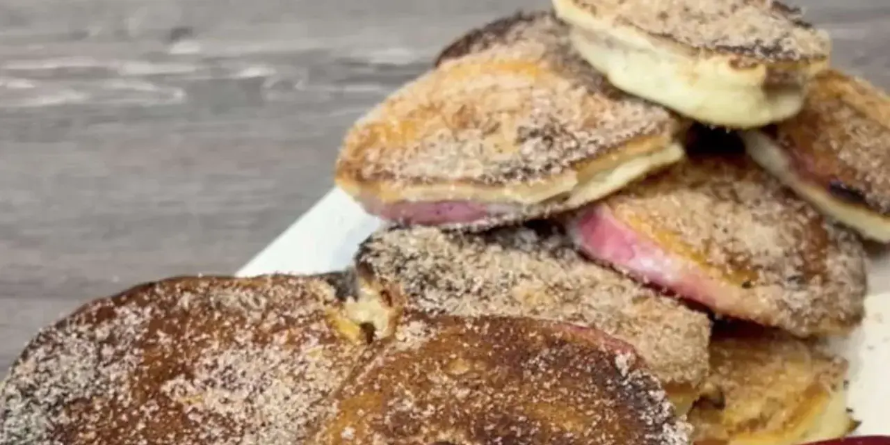 Ein Haufen goldbrauner, mit Zimt und Zucker bestreuter Apfelküchlein, die köstlich aussehen.