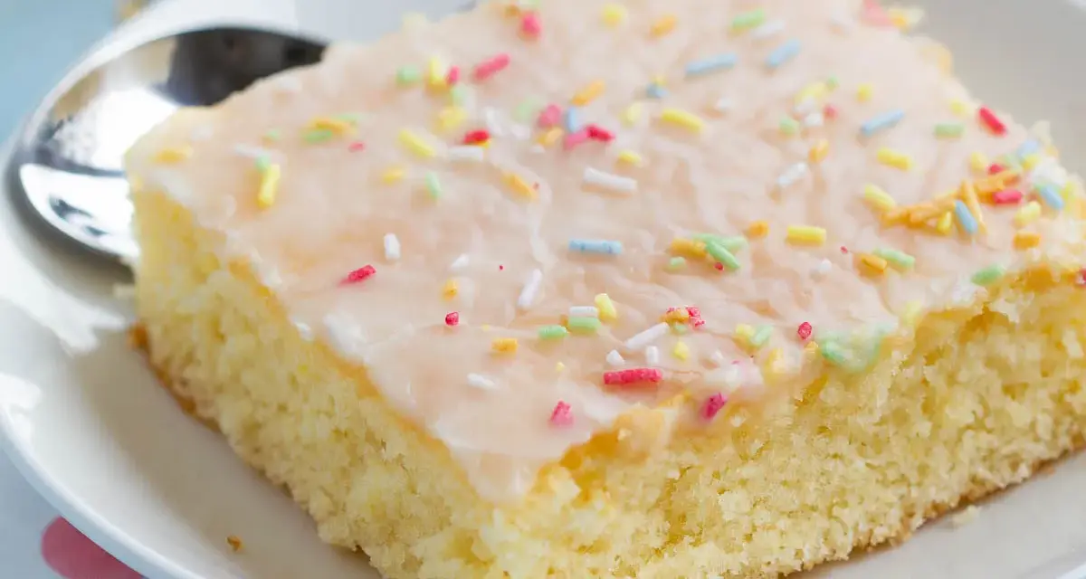 Ein Stück saftiger Fantakuchen mit Zuckerguss und bunten Streuseln, perfekt für das Fantakuchen Rezept.