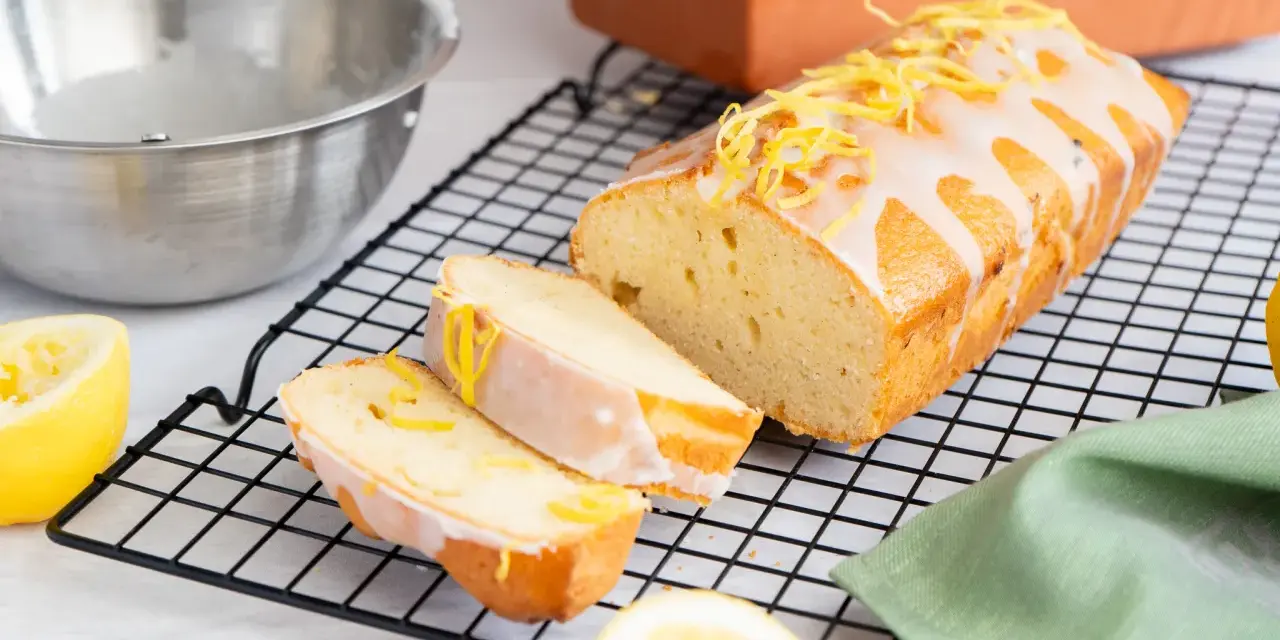Ein saftiger Zitronenkuchen, frisch aus dem Ofen, mit Zuckerguss und Zitronenschale verziert. Perfekt für ein Zitronenkuchen Rezept.
