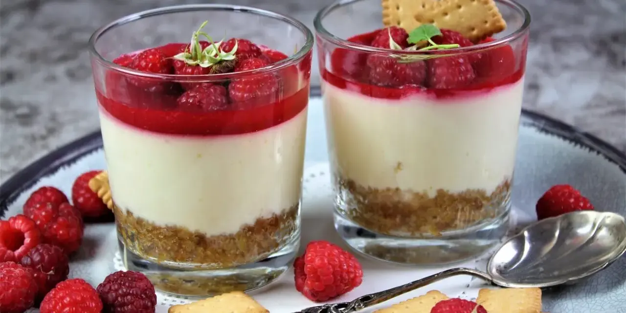 Zwei leckere Desserts im Glas mit Himbeeren und Keksen, ein süßer Genuss.